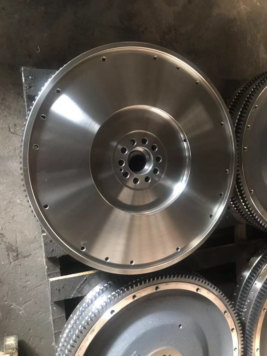 Flywheel face showing signal holes and ring gear; hole count and phase determine crankshaft position accuracy