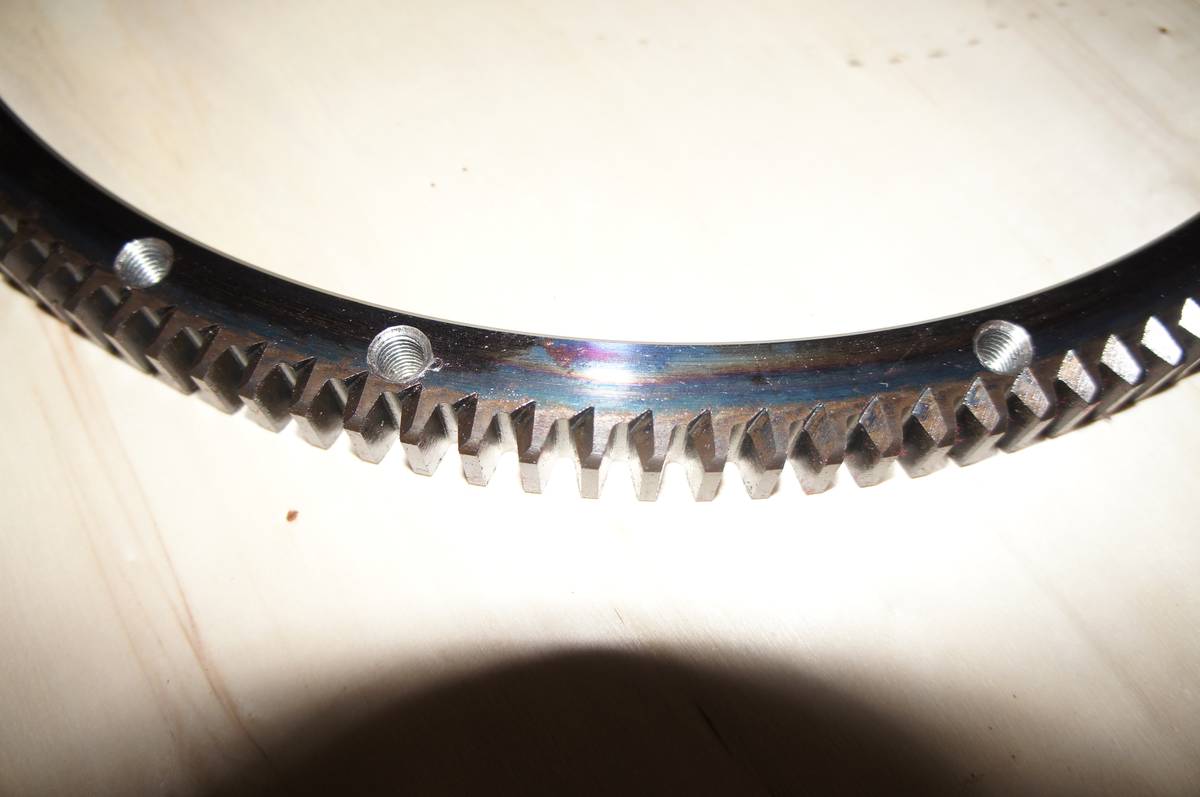 Close-up of ring gear tooth profile showing chamfered tips and threaded mounting holes